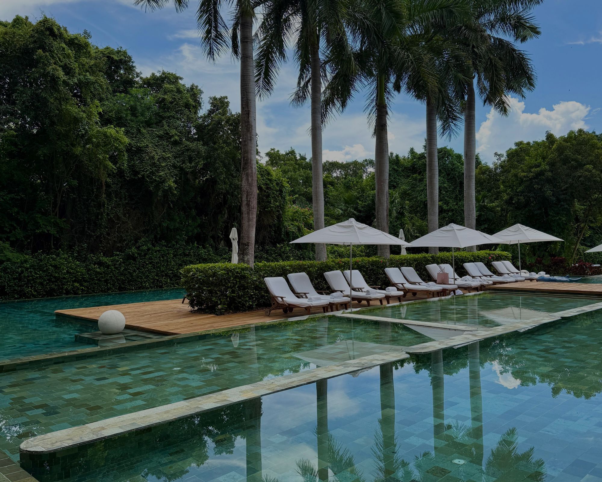 Luxury oceanfront pool at Grand Velas Riviera Maya surrounded by palm trees, cabanas, and Caribbean Sea views.