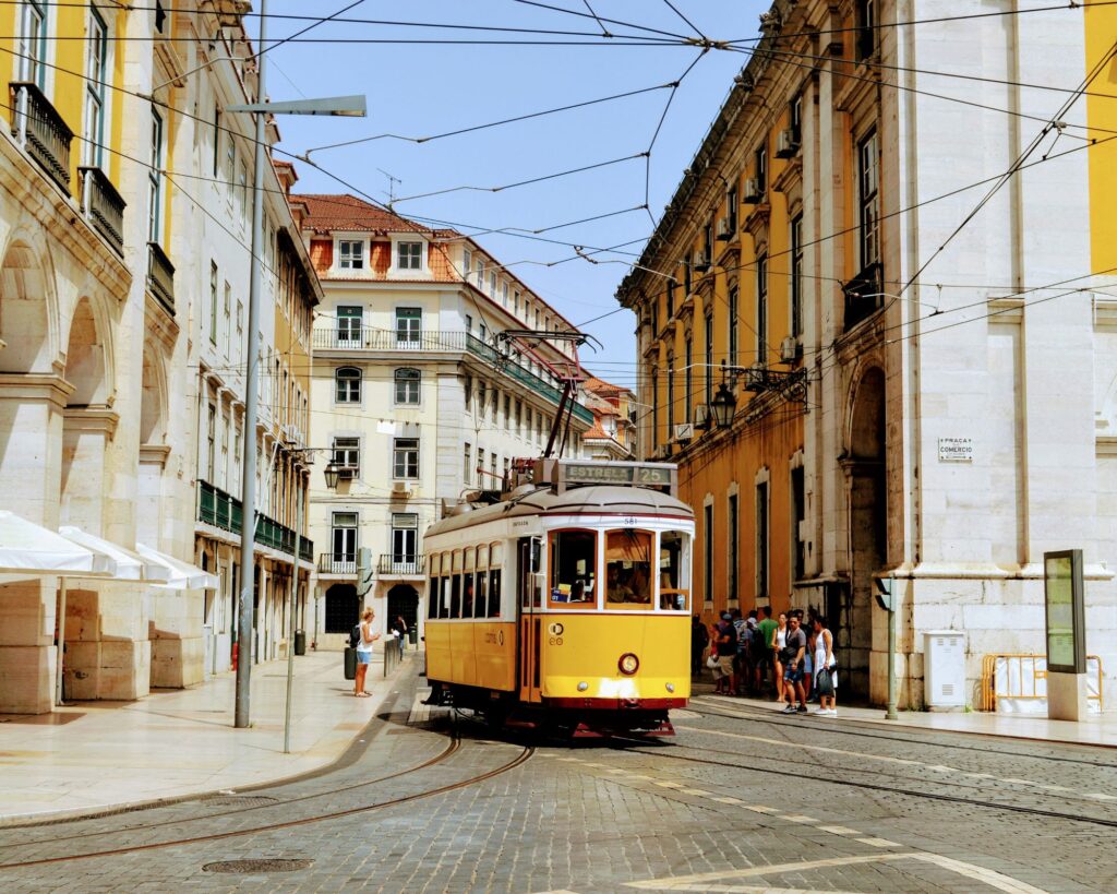 Historic yellow Tram 28 traveling through the narrow streets of Lisbon’s Alfama district.