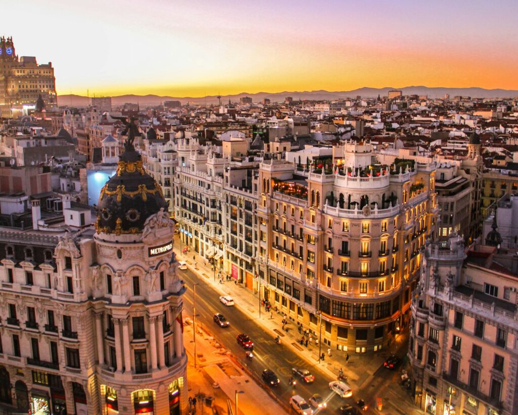 The Royal Palace of Madrid with its grand façade and spacious courtyard under a beautiful sunset.