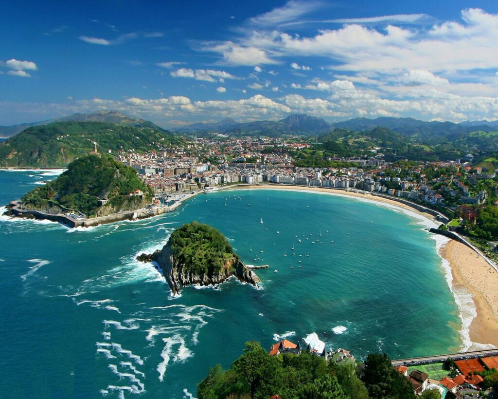 La Concha Beach in San Sebastián with turquoise water, golden sand, and surrounding green hills.